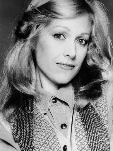 A black and white photo of a woman wearing a sweater and scarf.