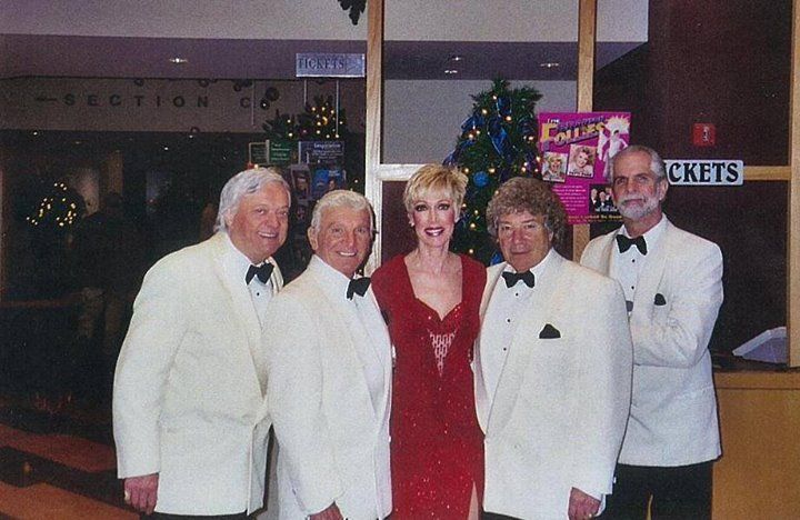 A group of people posing for a picture in front of a sign that says tickets
