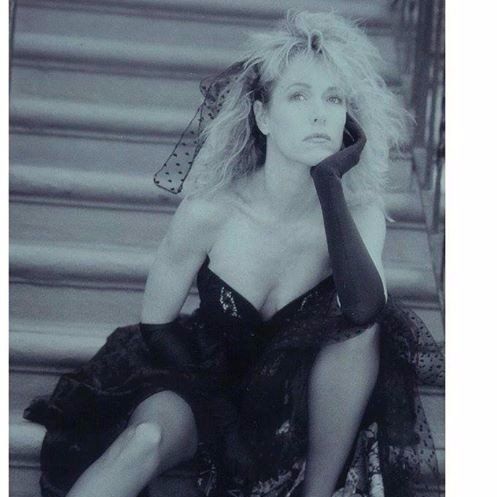 A woman in a black dress is sitting on a set of stairs