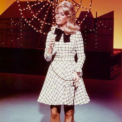 A woman in a plaid dress is singing into a microphone