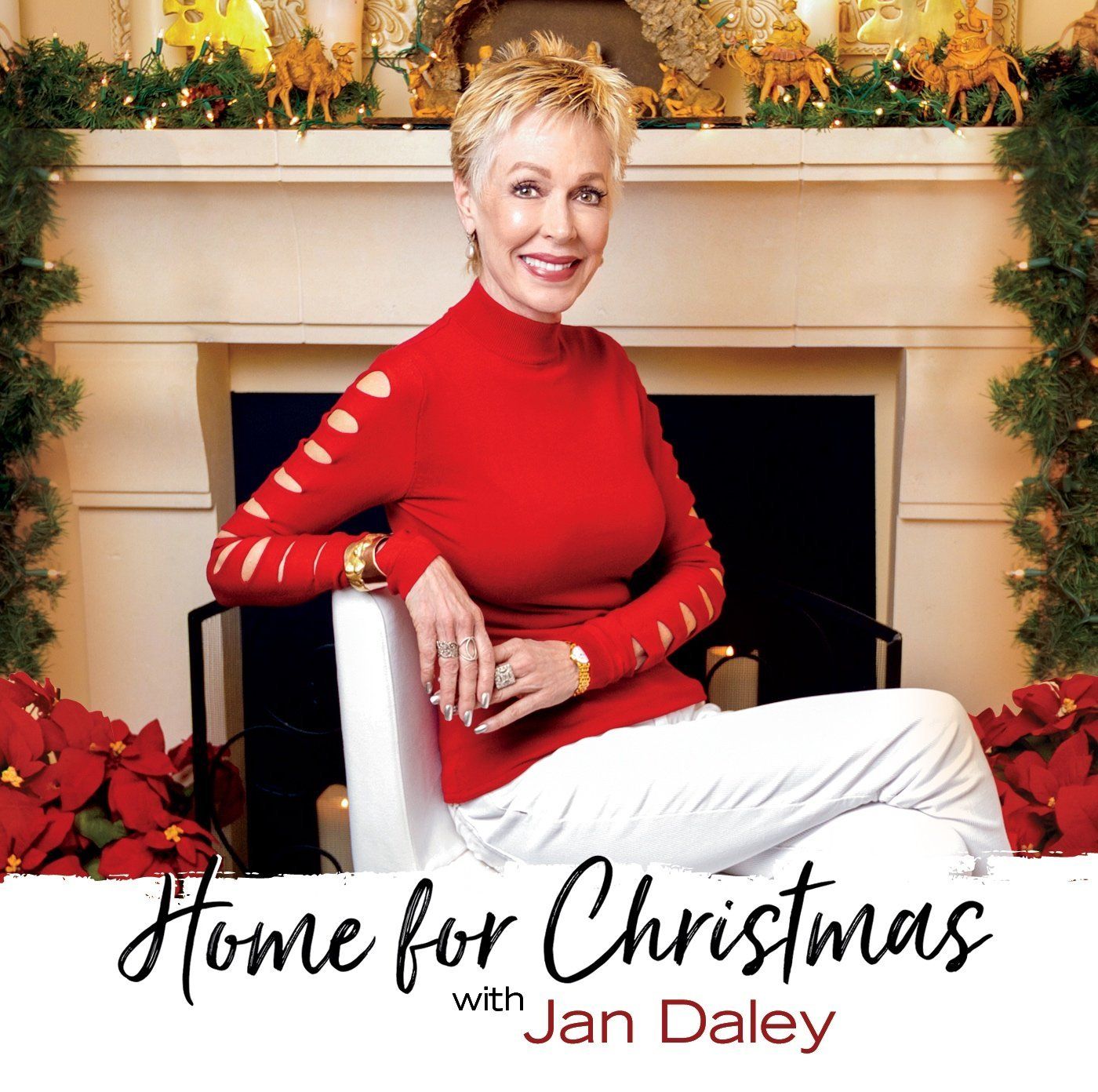 A woman in a red sweater is sitting in front of a fireplace.