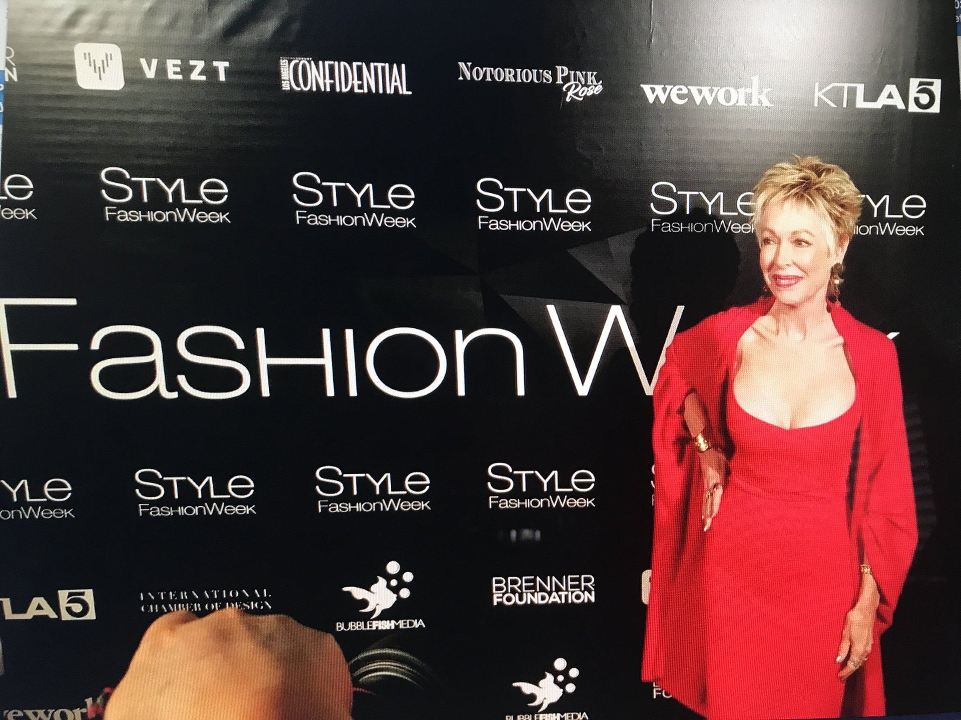 A woman in a red dress is standing in front of a fashion wall