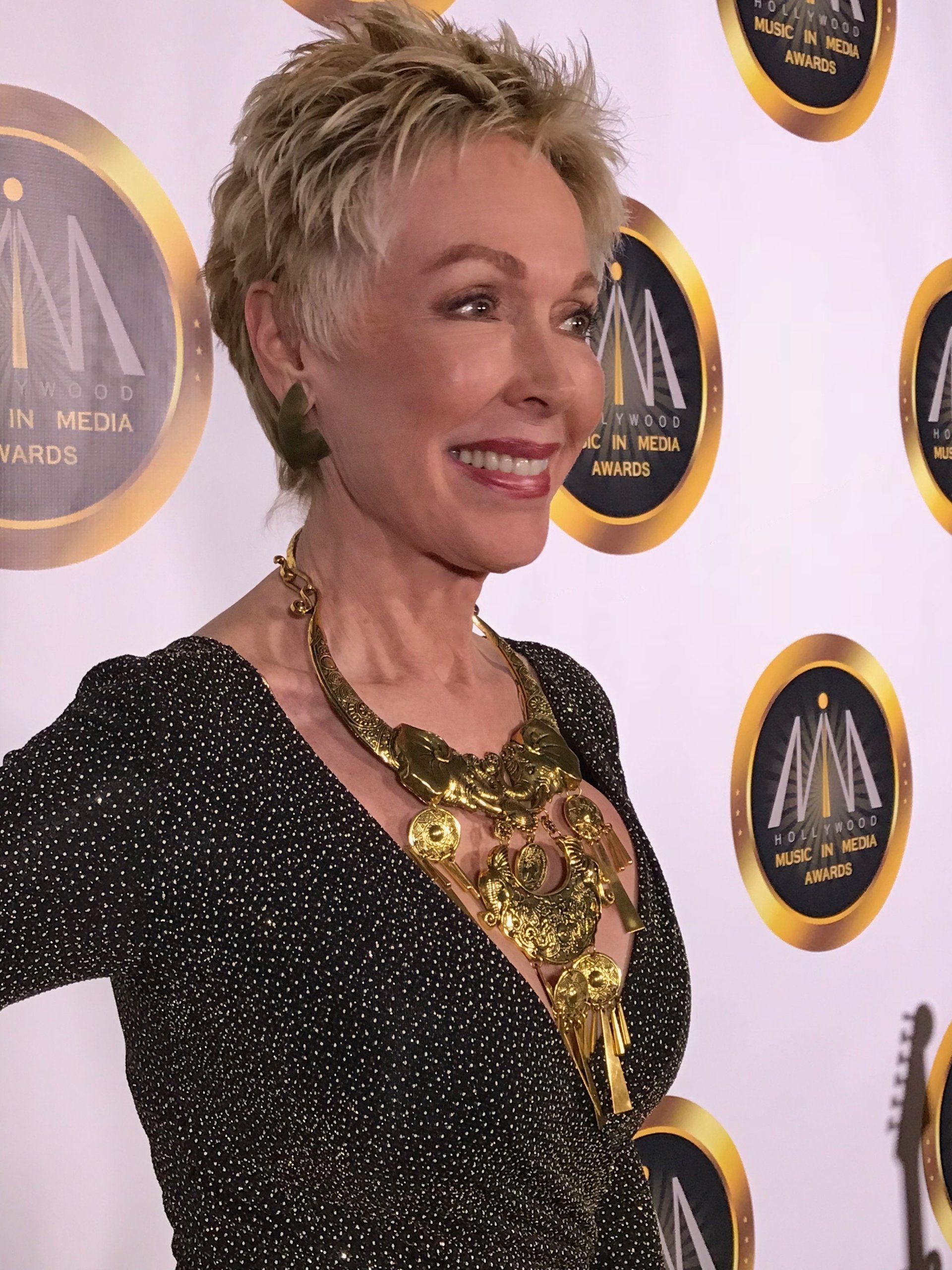 A woman wearing a black and gold dress and a gold necklace