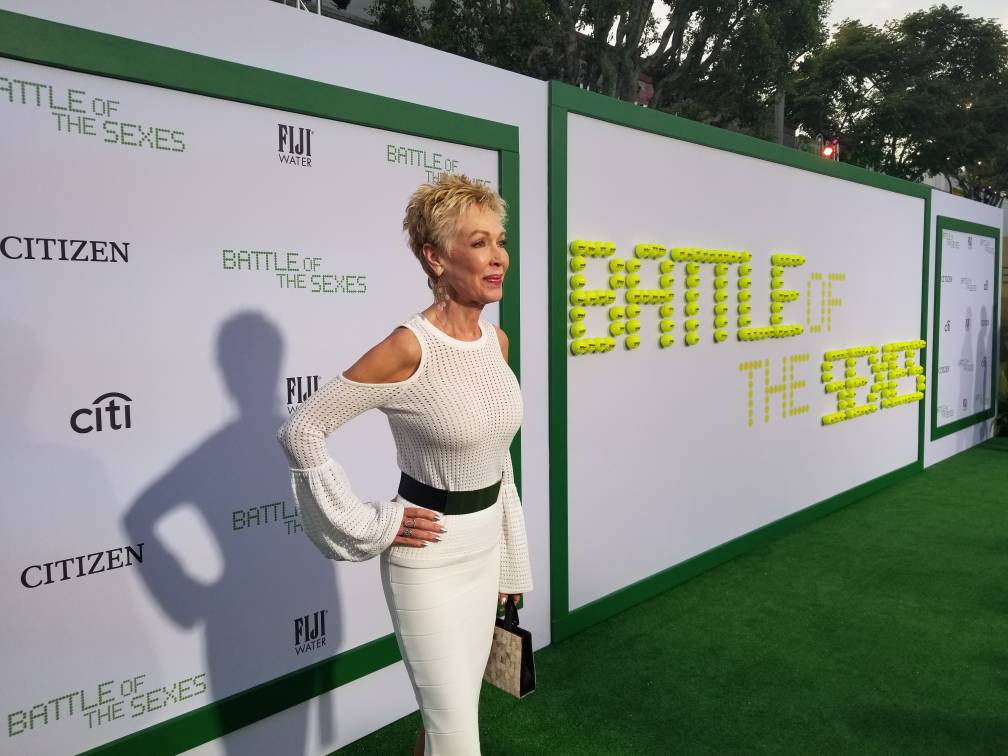 A woman in a white dress is standing on a green carpet.