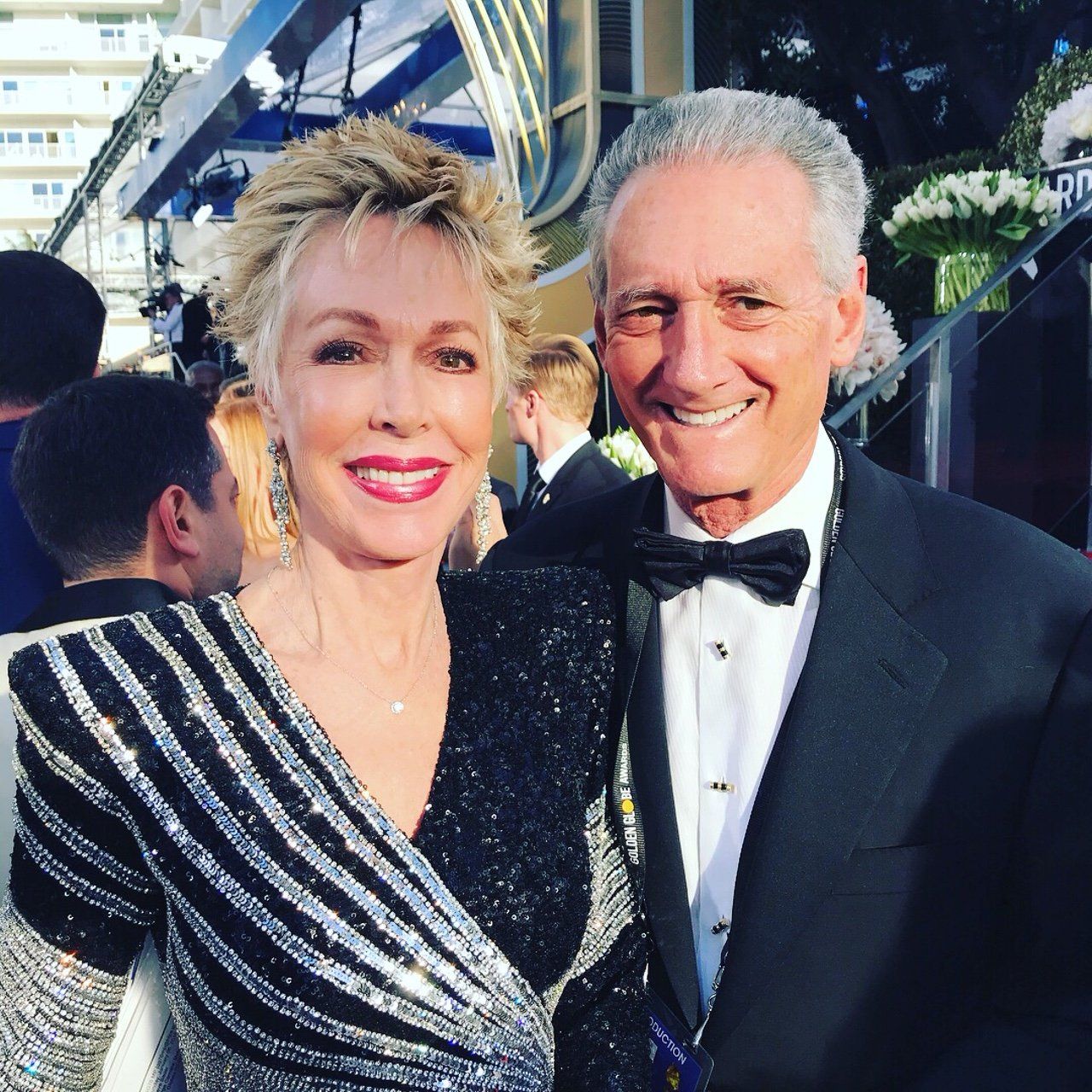 A man in a tuxedo and a woman in a dress pose for a picture