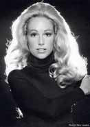 A black and white photo of a woman with long blonde hair wearing a black turtleneck.