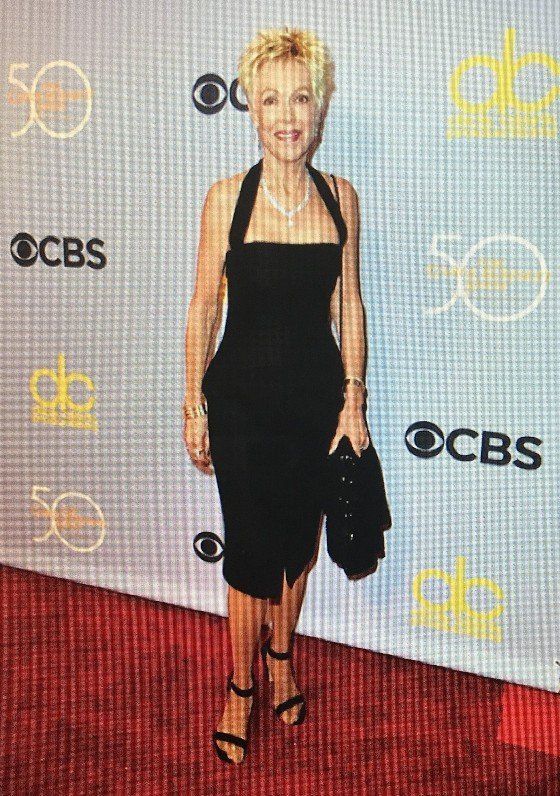 A woman in a black dress is standing on a red carpet.