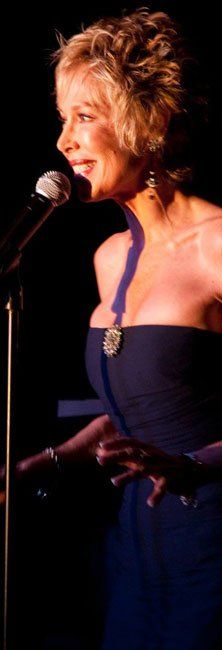 A woman in a blue dress is singing into a microphone