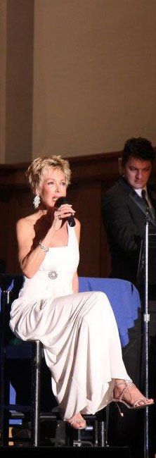 A woman in a white dress is singing into a microphone