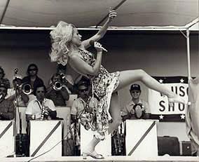 A woman is singing into a microphone on a stage in front of a crowd.