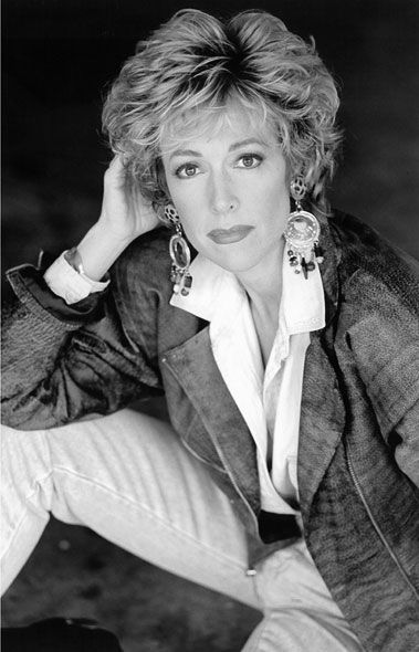 A black and white photo of a woman wearing a jacket and earrings