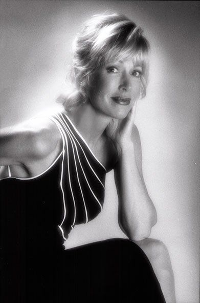 A woman in a black and white photo is sitting down with her hand on her face.