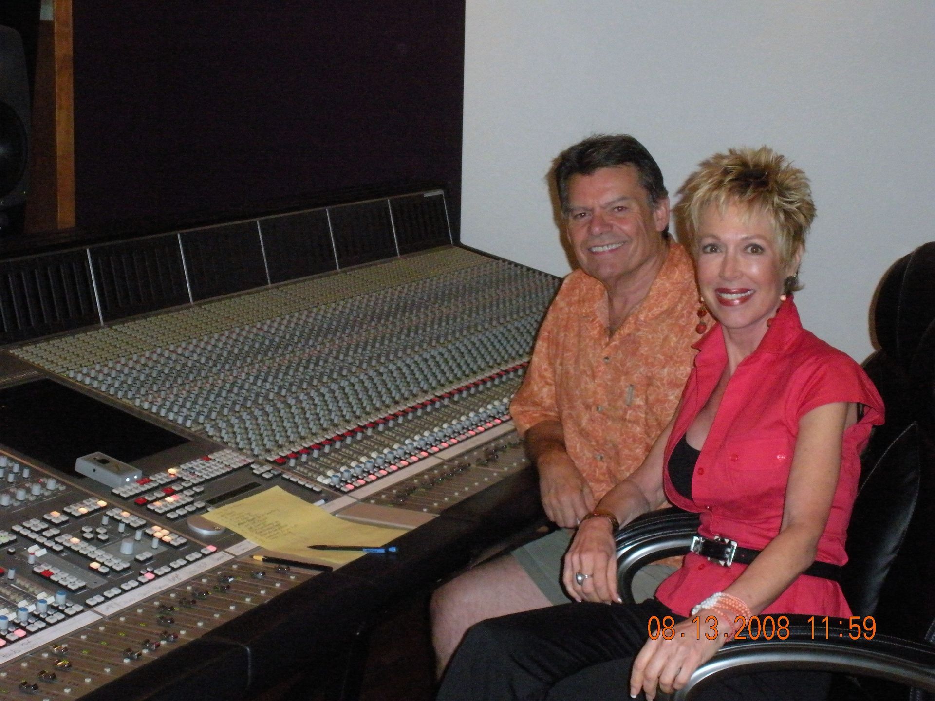 A man and a woman sit in front of a sound board