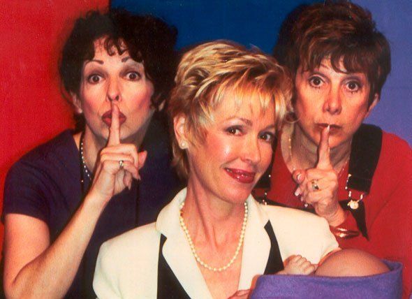 Three women are posing for a picture with their fingers on their lips