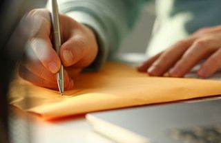 man writing on envelope