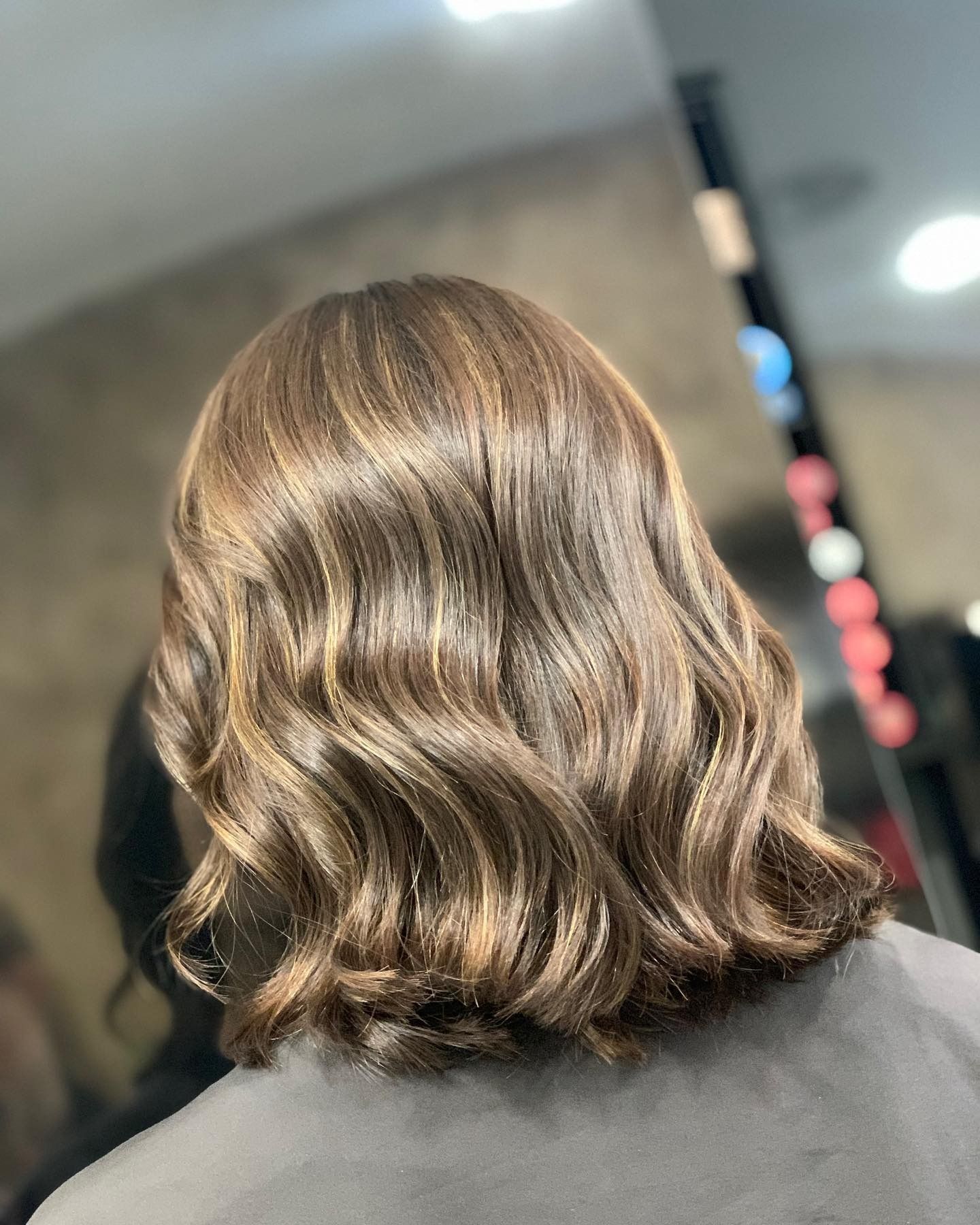 Donna con capelli castani ondulati in un salone di bellezza.