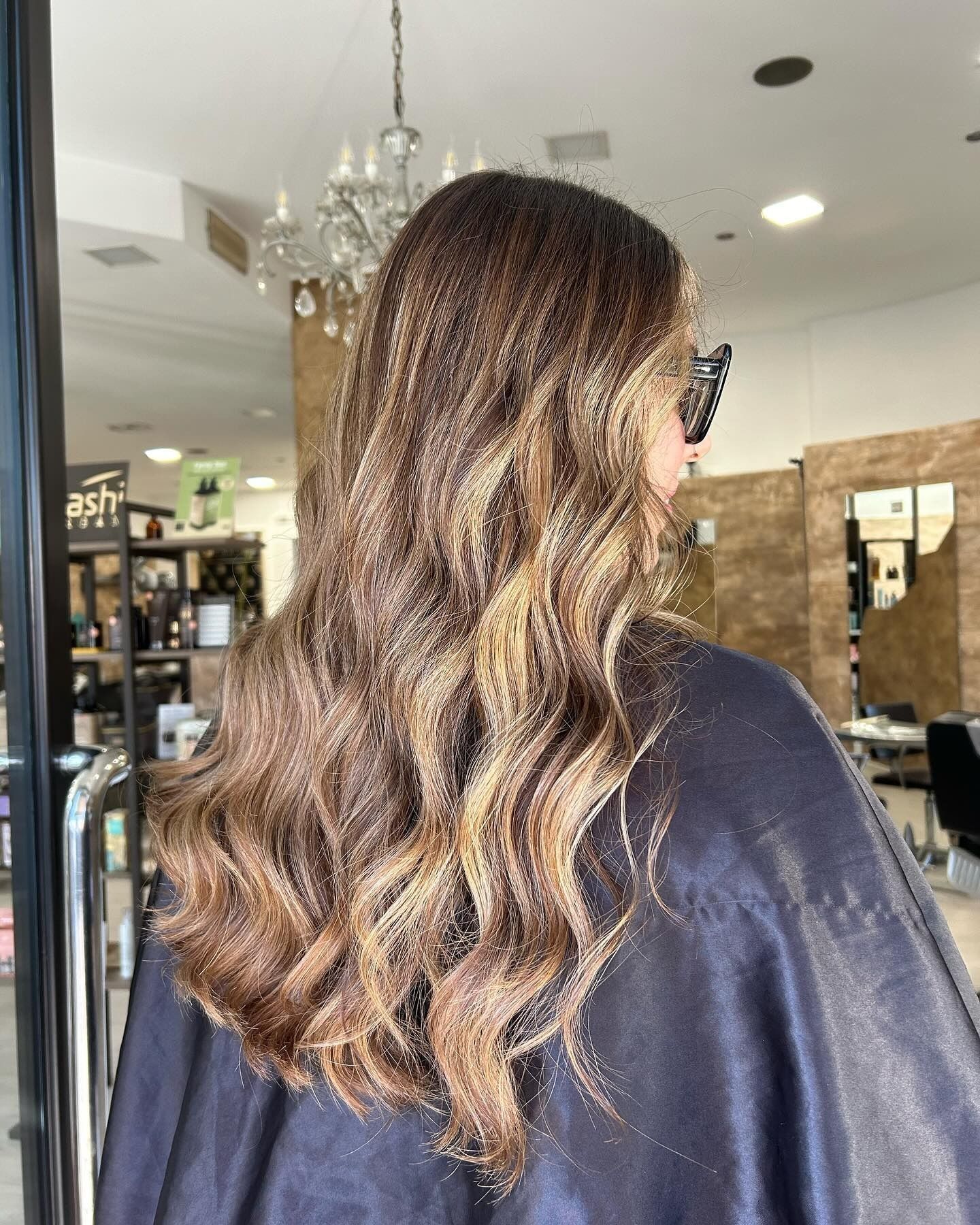 Donna con lunghi capelli castani ondulati con riflessi biondi, in un salone.