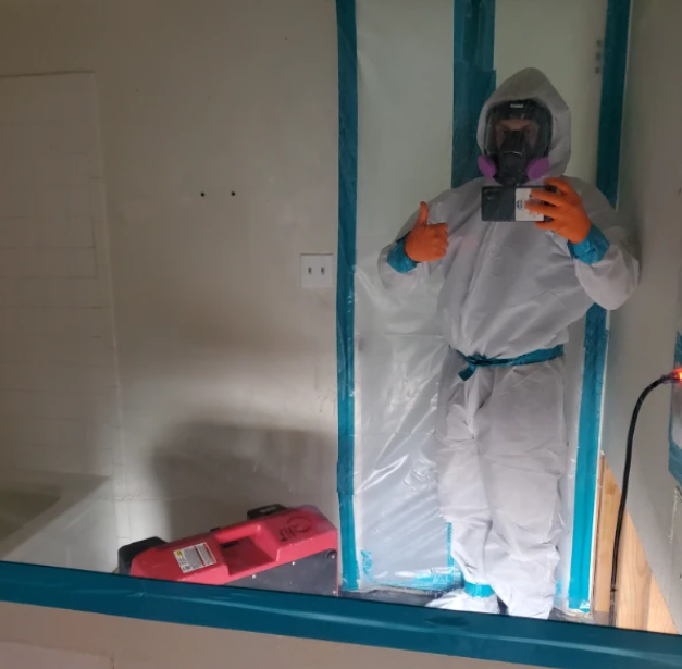 A man in a protective suit is taking a picture of himself in a mirror