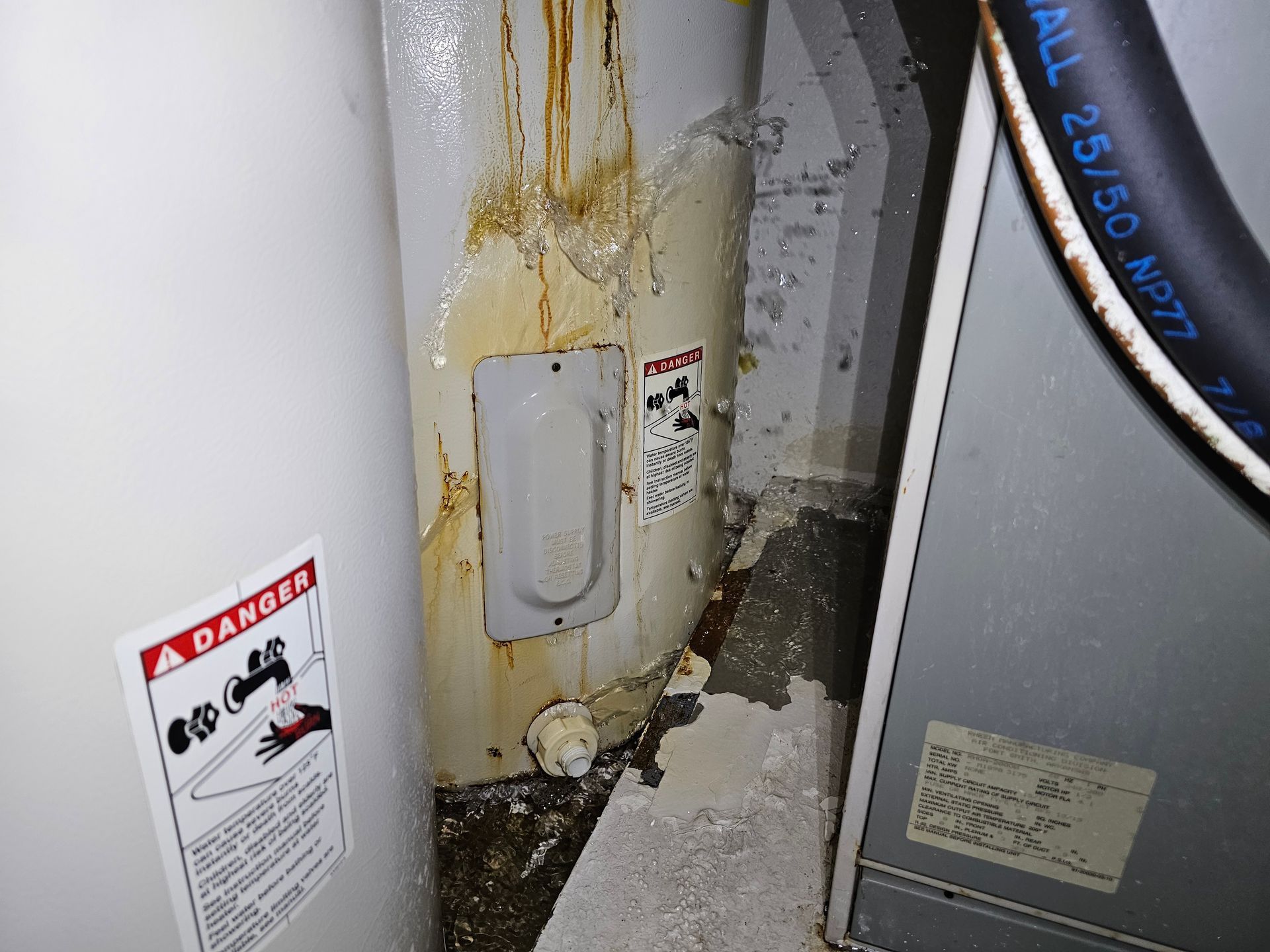 A close up of a water heater with a danger sign on it.