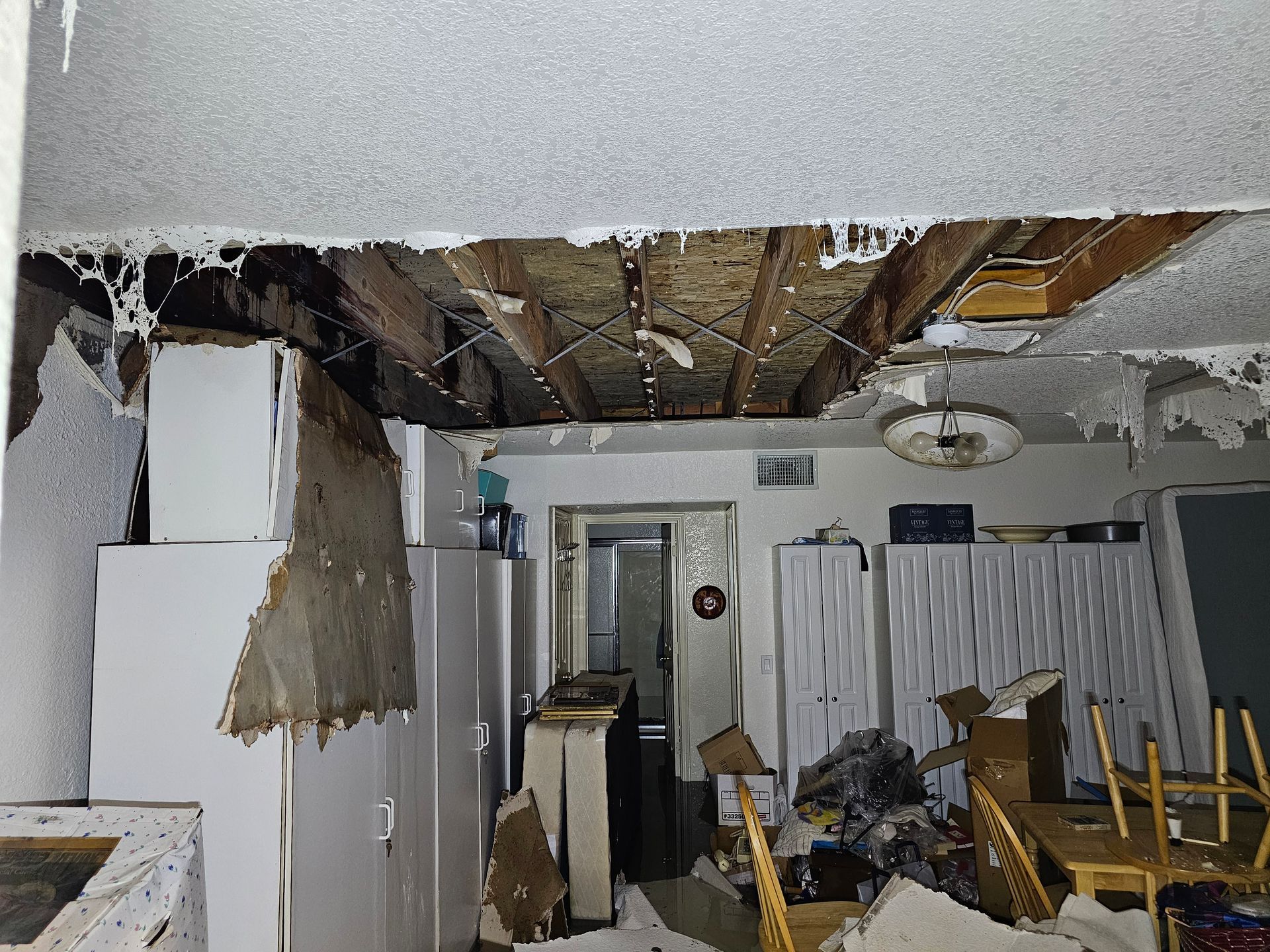 A room with a hole in the ceiling and a lot of furniture.