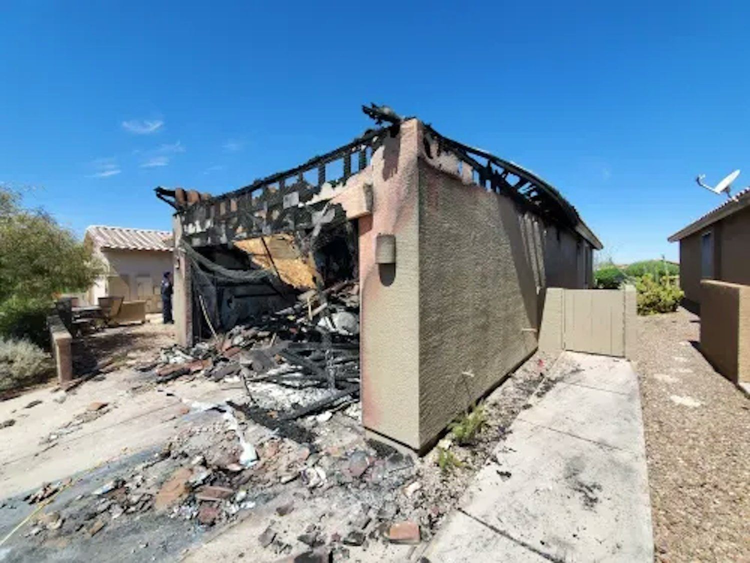 A house that has been damaged by a fire is sitting on the side of the road.