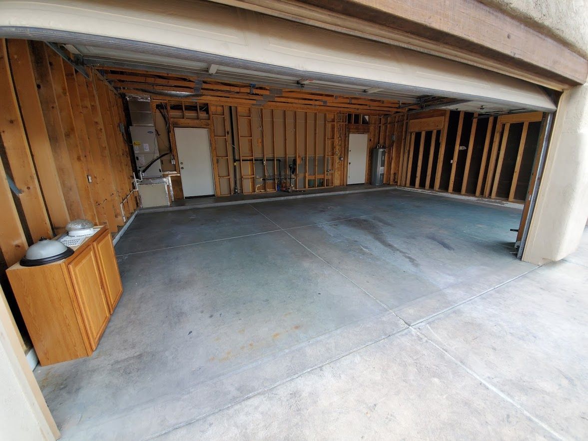 An empty garage with a wooden wall and a concrete floor.