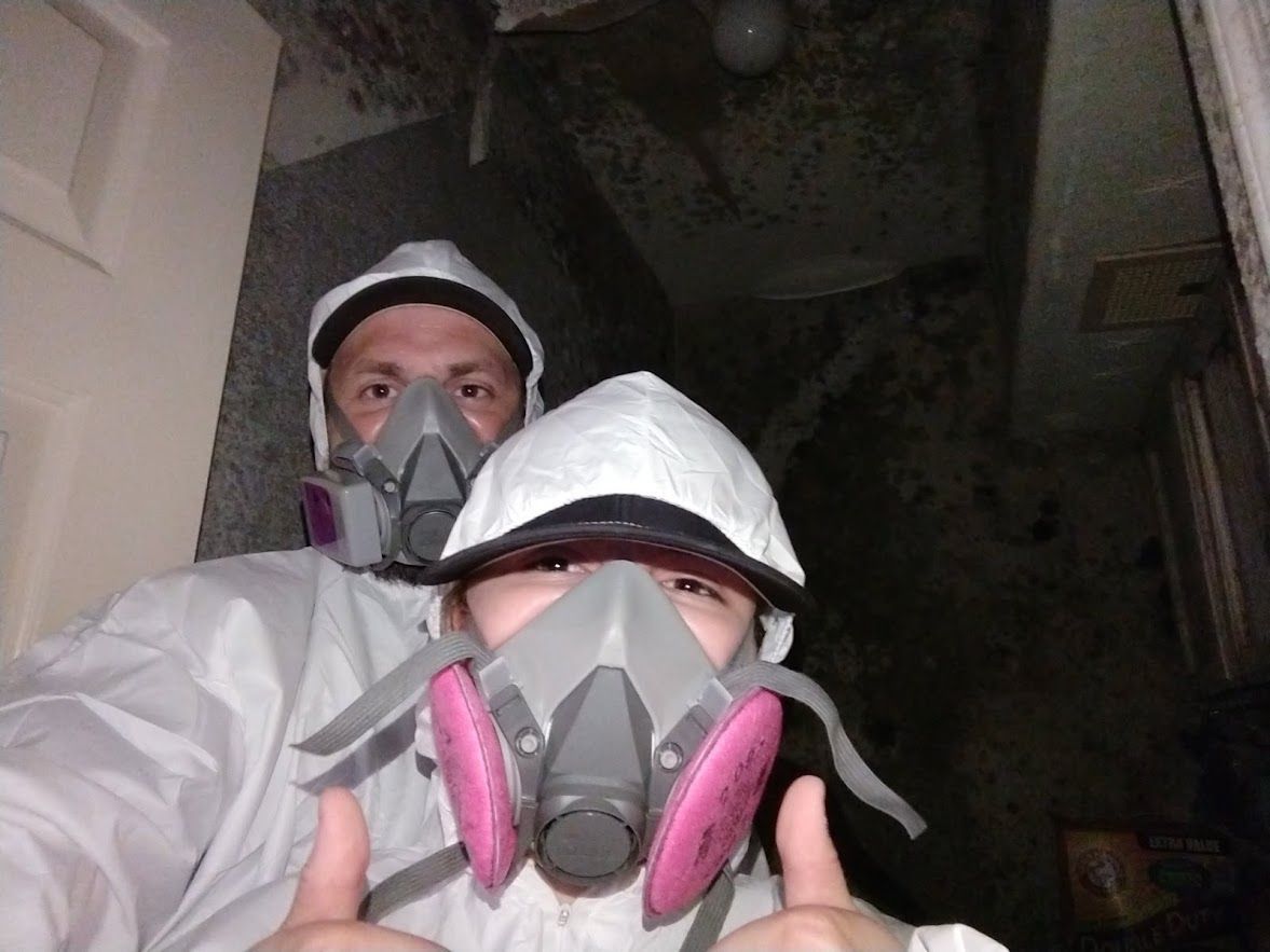 A man and a woman wearing gas masks are giving a thumbs up