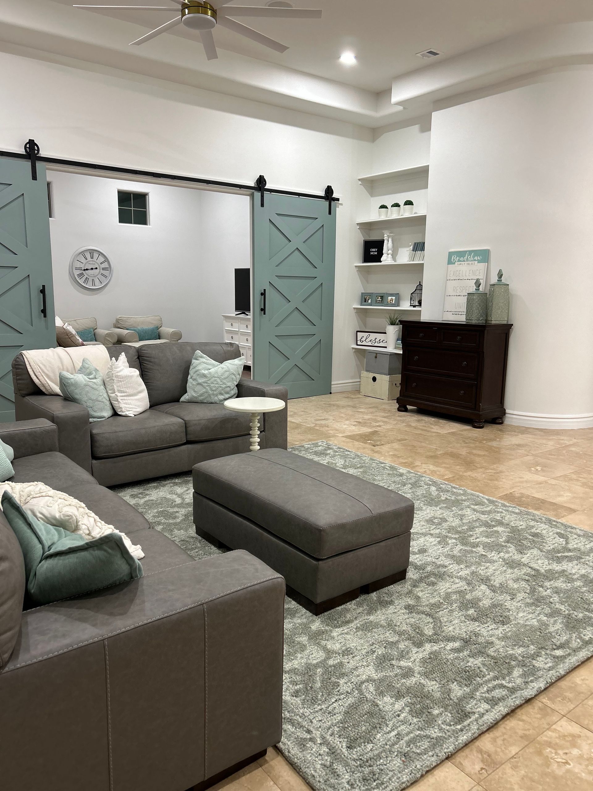A living room with a couch , ottoman , rug and sliding barn doors.