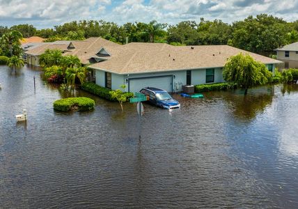 A car is parked in front of a flooded house.