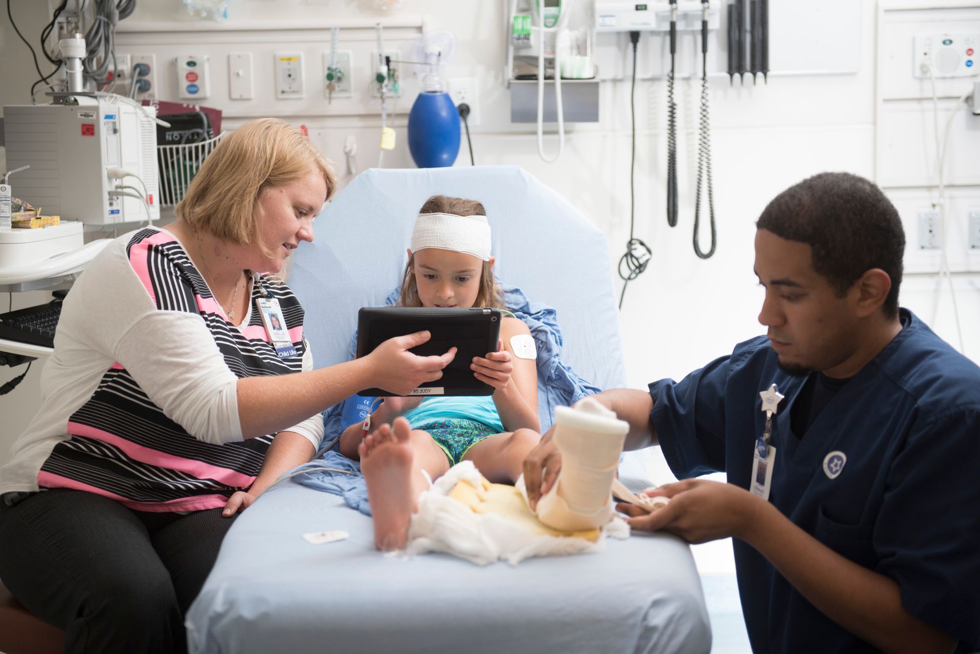 A child life professional connects with a young patient getting a cast put on their leg.