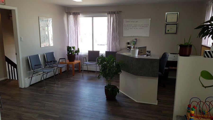 Une salle d'attente avec des chaises, un bureau et une plante.