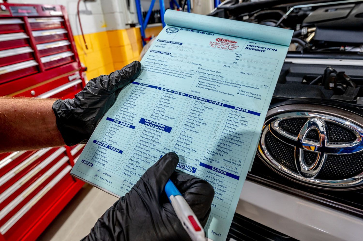 A Person Is Writing On A Piece Of Paper - Prospect, SA - Topgear Automotive Services