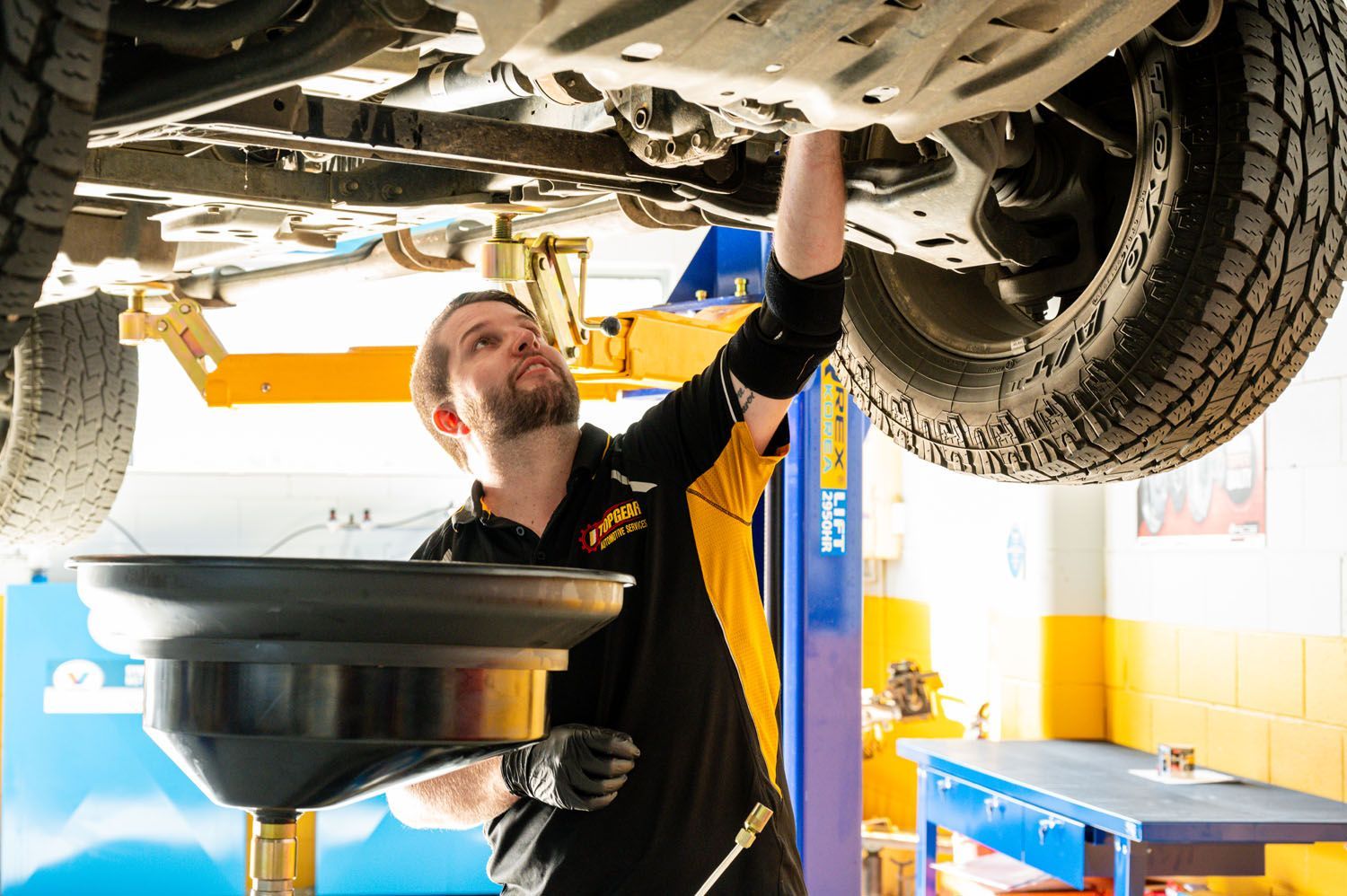 A Man Is Working Under A Car In A Garage - Prospect, SA - Topgear Automotive Services
