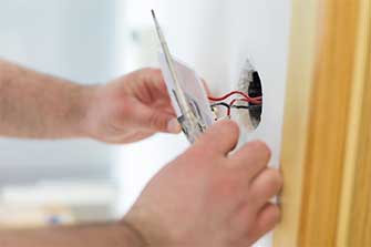 Handy man installing light switch after home renovation — Electric Contractors in Portland, Maine