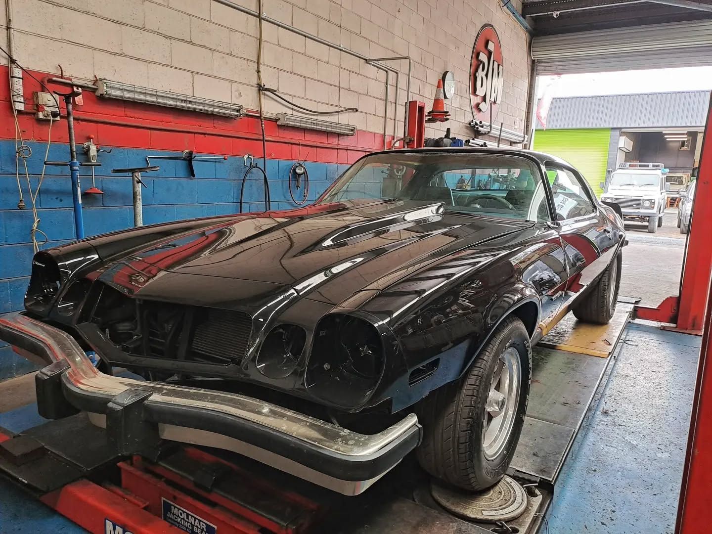 Black Classic Car on a Lift in a Garage — BJM Mechanical Mufflers & Tyres in Oxenford, QLD