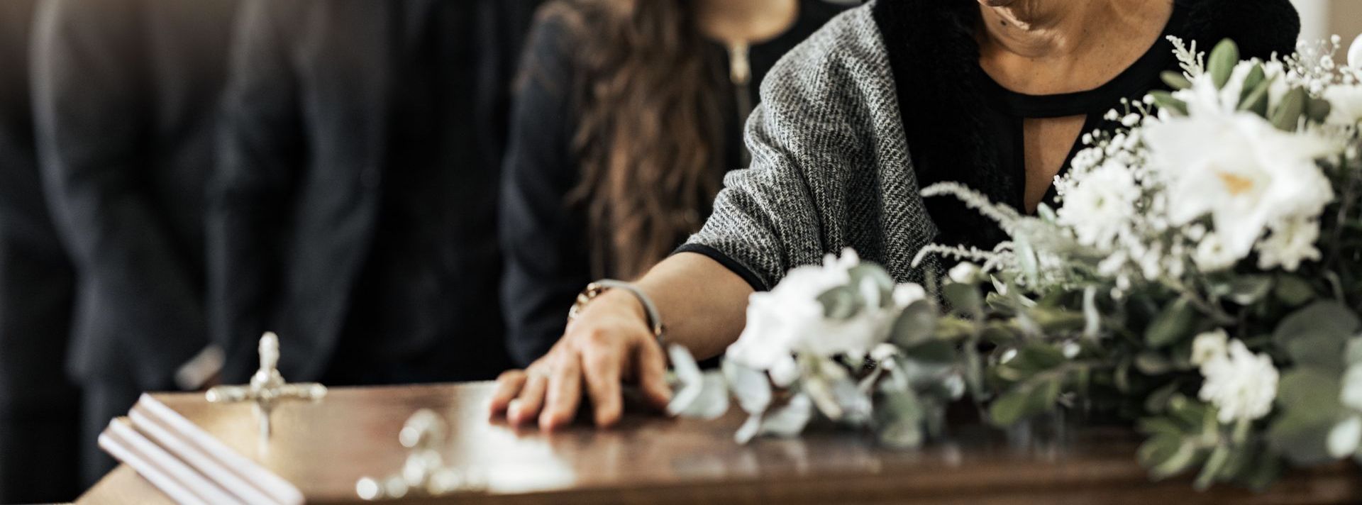 A woman is standing next to a coffin at a funeral.