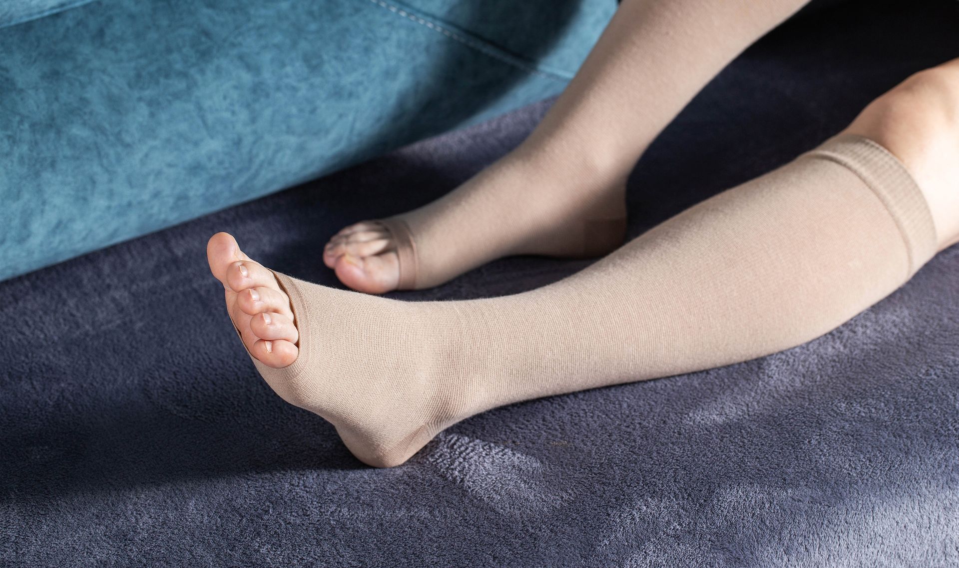 A person wearing compression stockings is sitting on a couch.