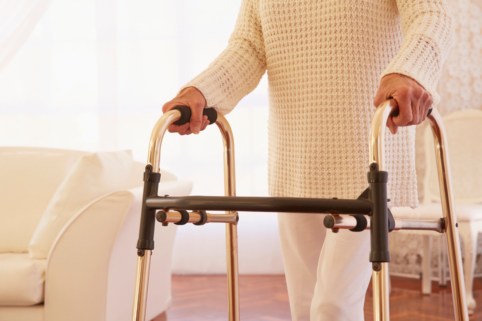 An elderly woman is using a walker in a living room.