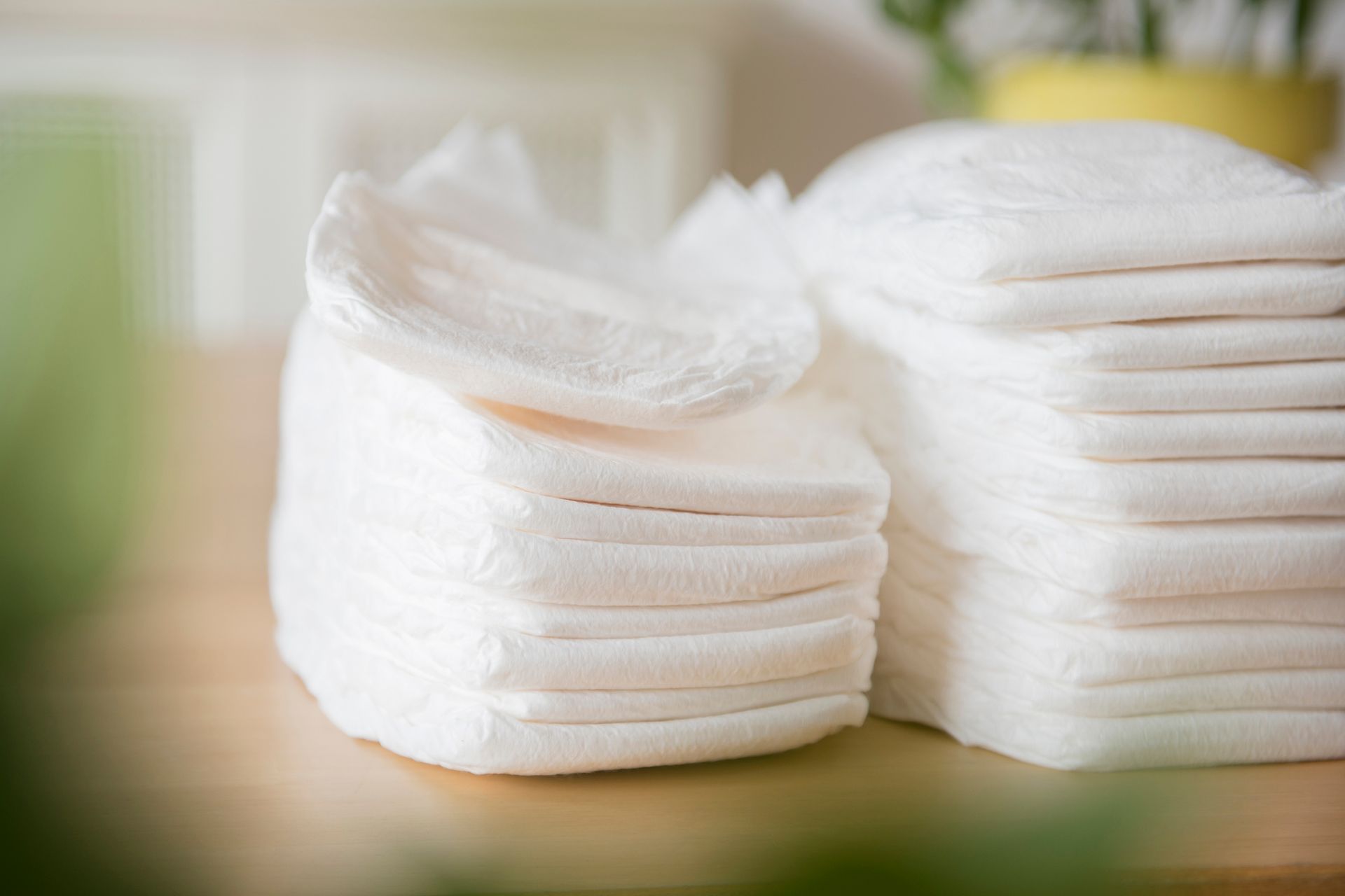 Two stacks of diapers are sitting on a wooden table.