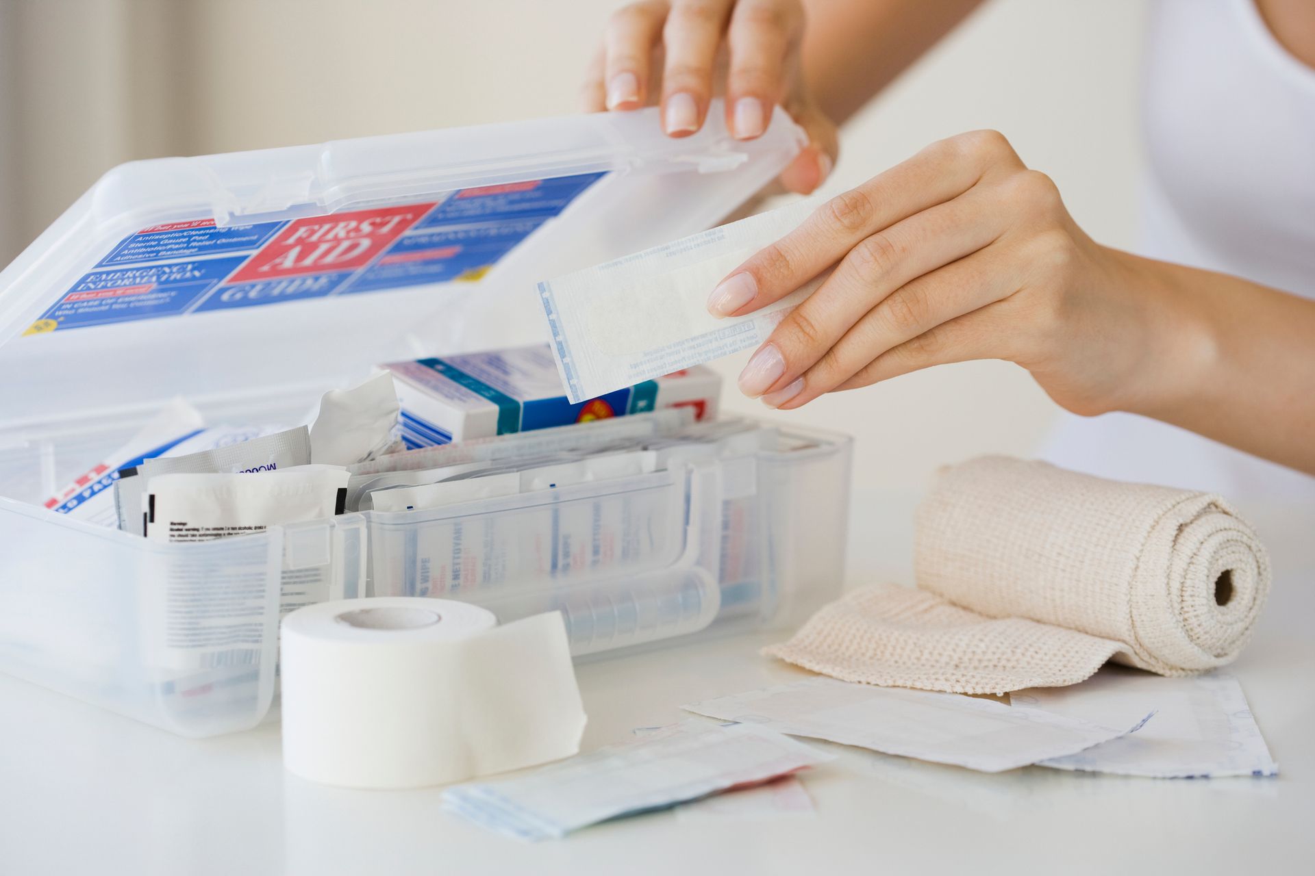 A woman is opening a first aid kit on a table.