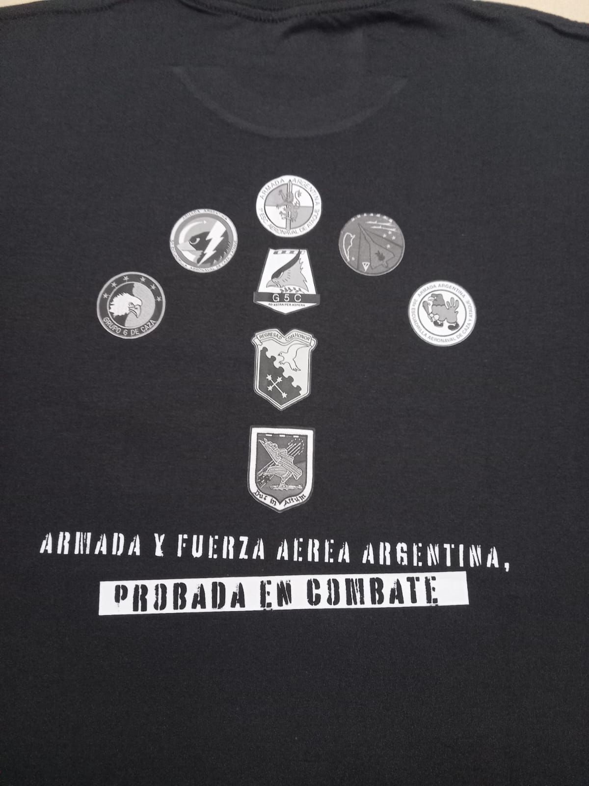 Camiseta negra con siluetas de barcos blancos y texto en español: «Malvinas, Atlántico Sur». Manga con logotipo.