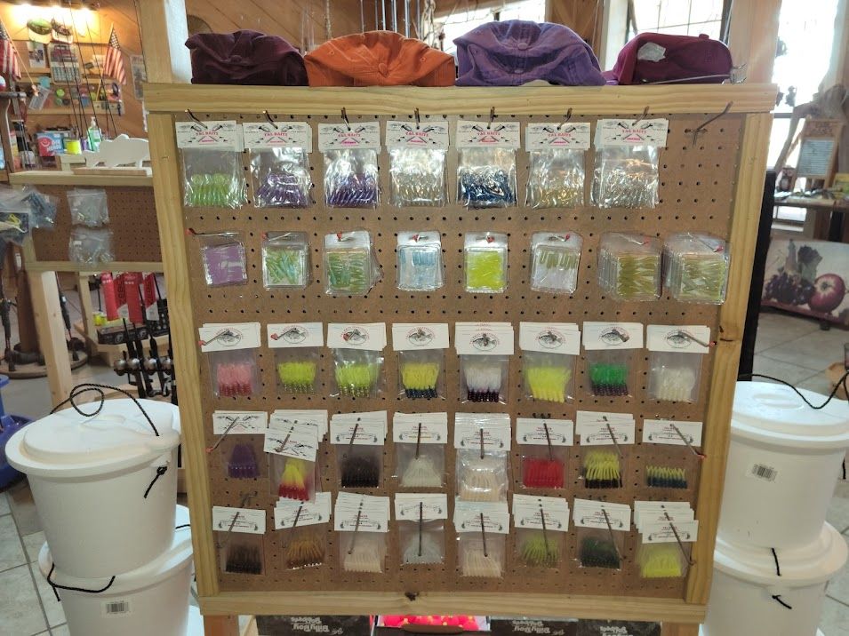 A pegboard display rack holds rows of small, colorful packages of craft beads or supplies, with white buckets nearby.