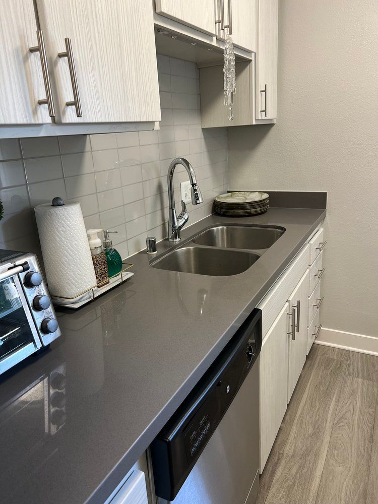 A kitchen with two sinks , a toaster oven , and a dishwasher.