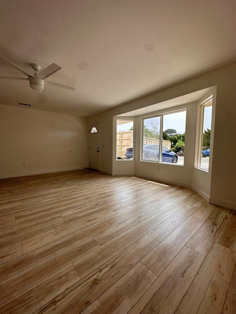 An empty living room with wooden floors and a ceiling fan.