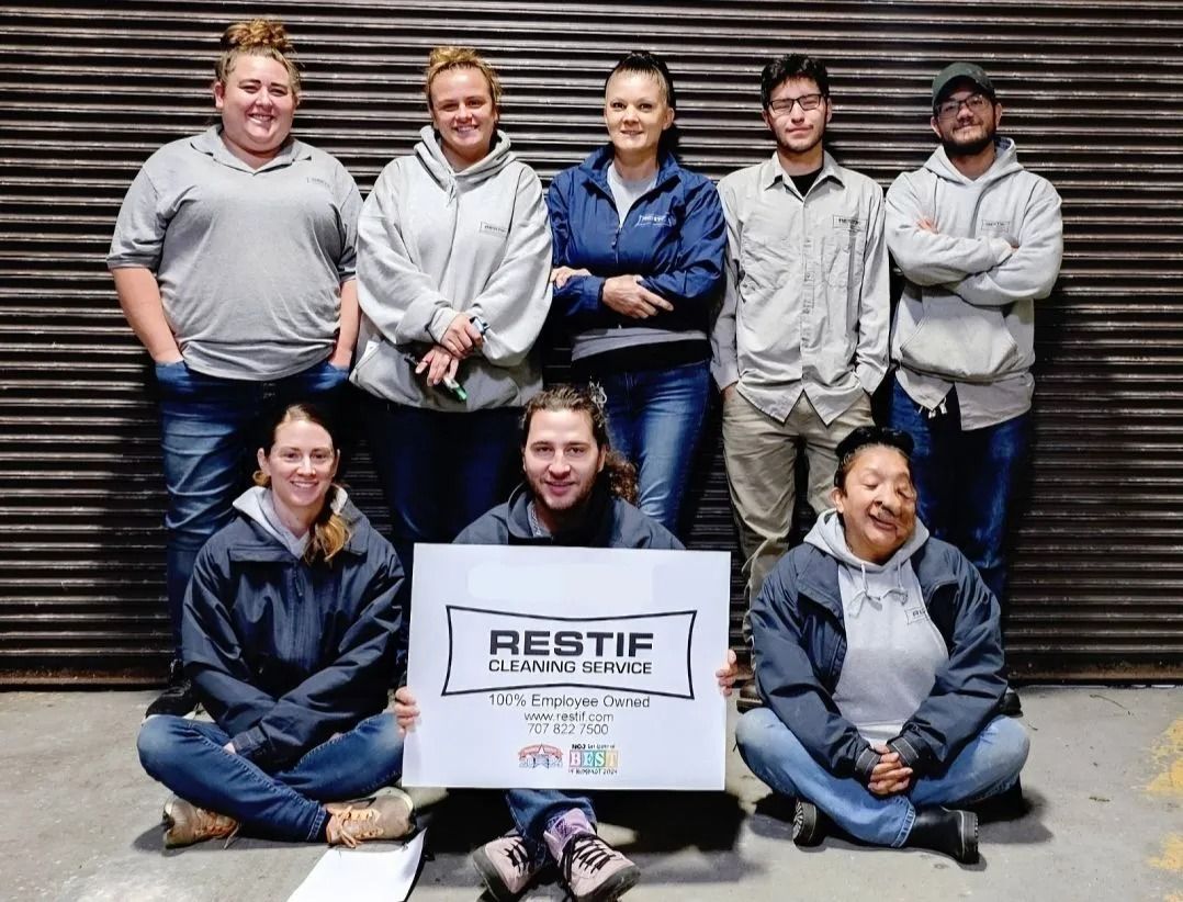 A group of people sitting on the ground holding a sign that says Restif