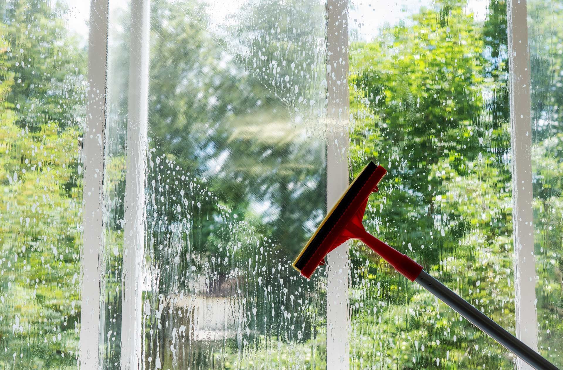 A person is cleaning a window with a squeegee.