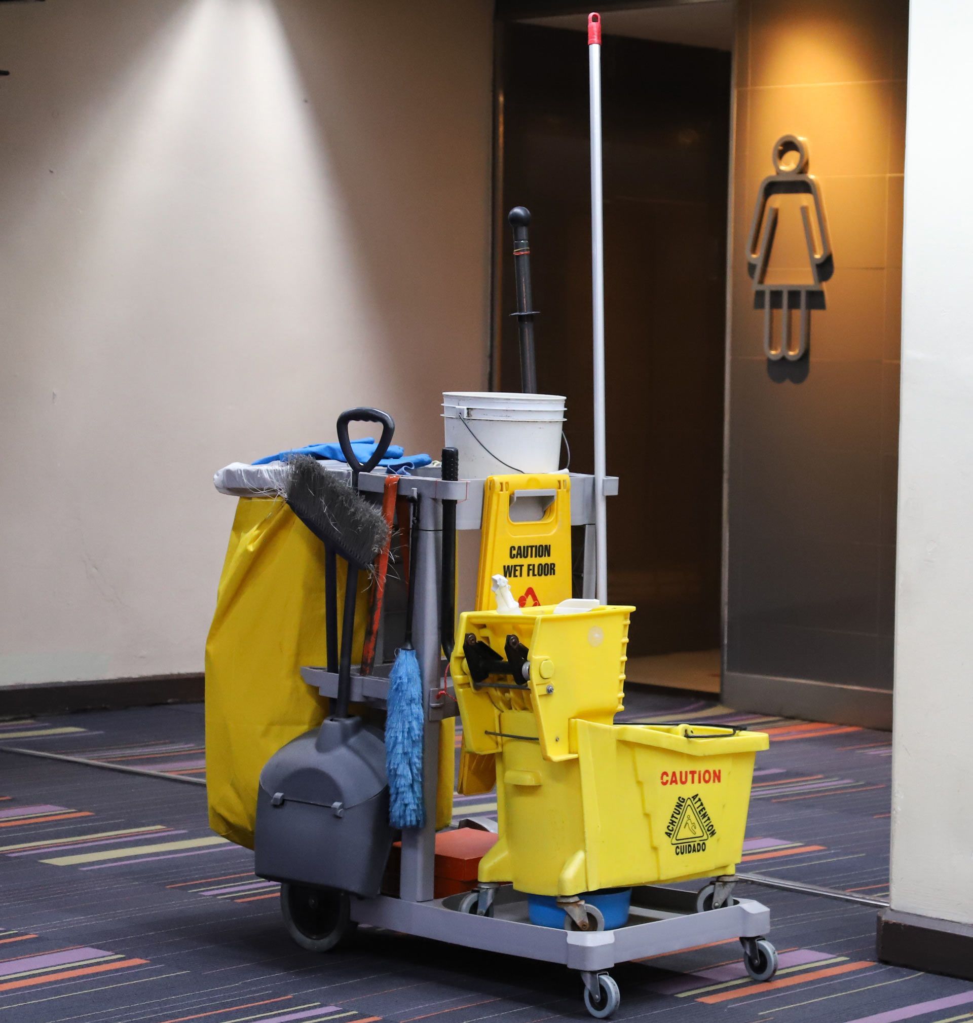 A cleaning cart with a yellow bucket that says caution on it