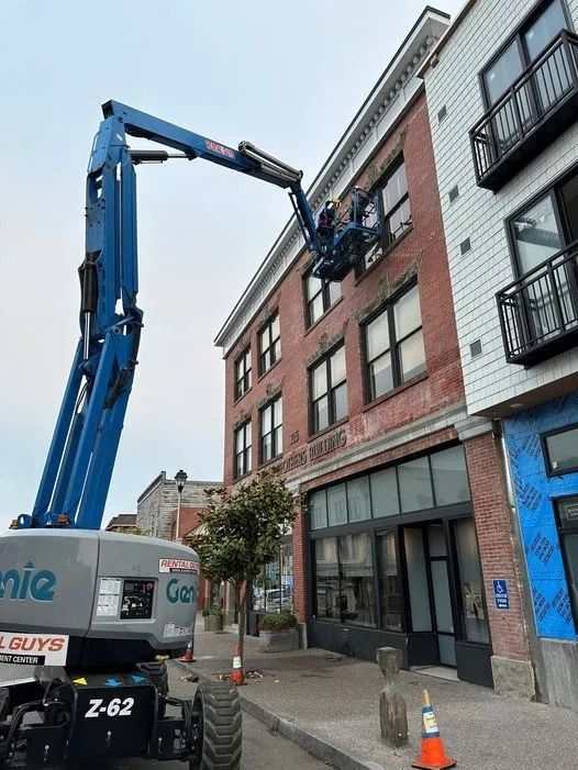 A man is working on the side of a building with a crane.