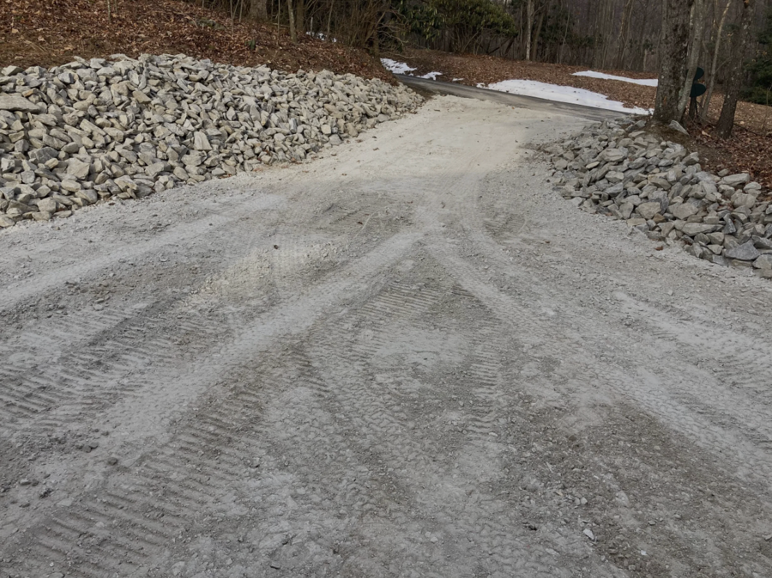 A dirt road with a pile of rocks on the side of it.