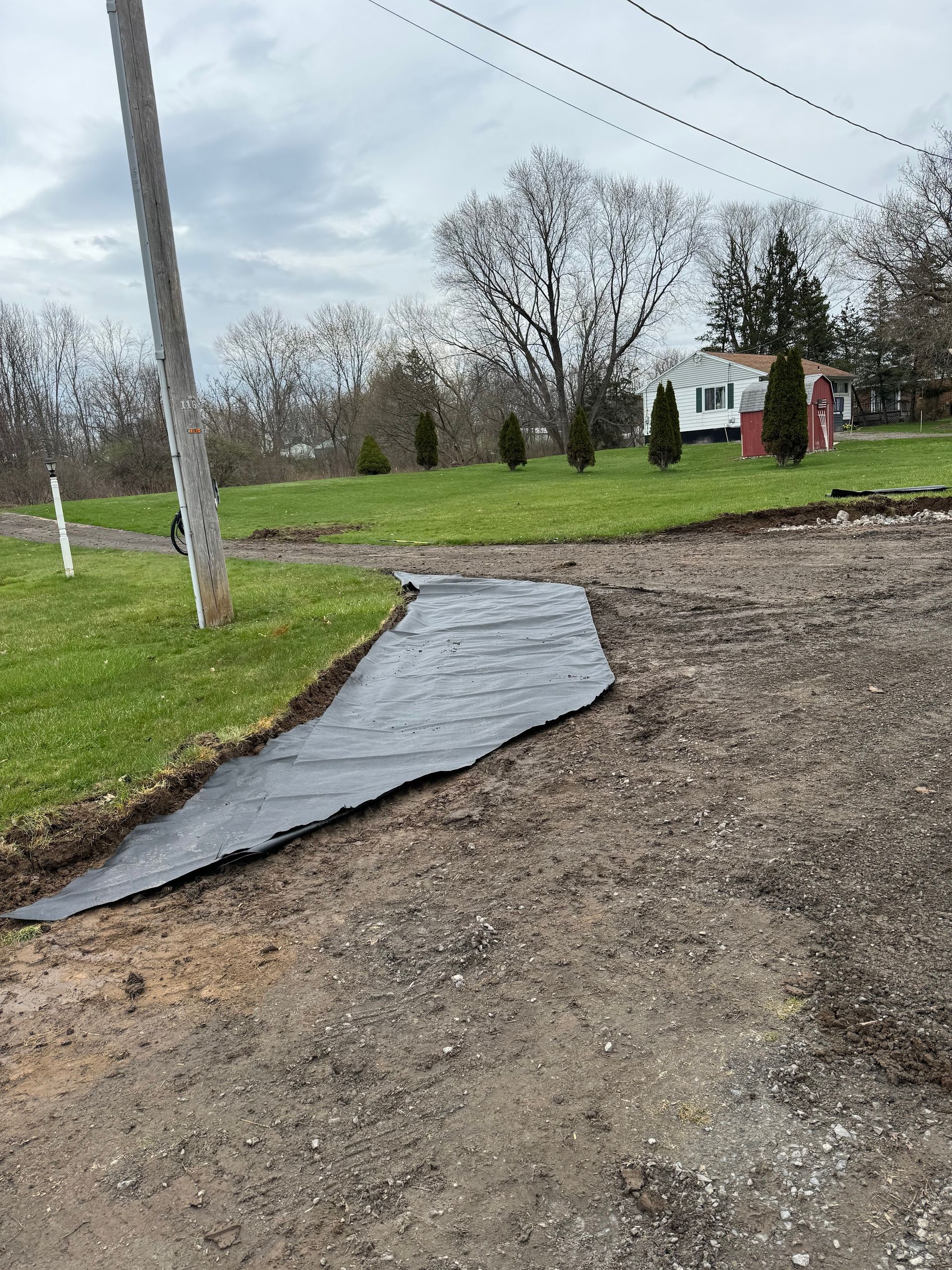 A black tarp is laying on the side of a dirt road.